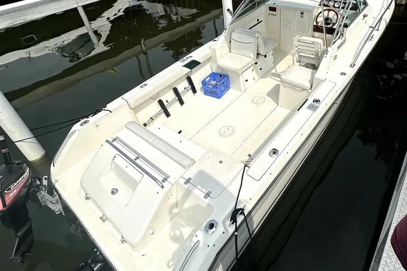 Slide: The Image of 1999 Pursuit 2460 Denali boat docked, featuring spacious deck and seating. - 1