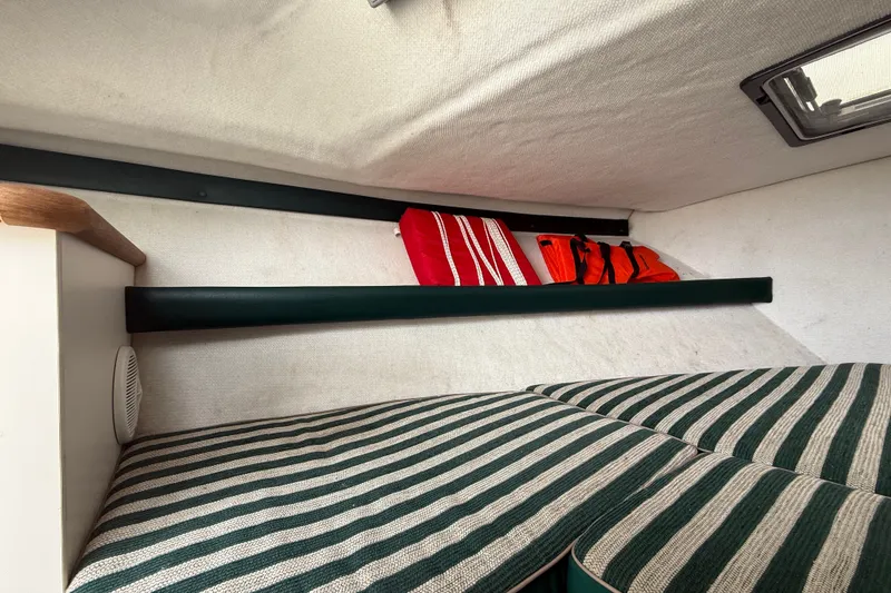 Slide: The Image of Interior cabin of 1999 Pursuit 2460 Denali boat with striped cushions and storage shelf. - 26