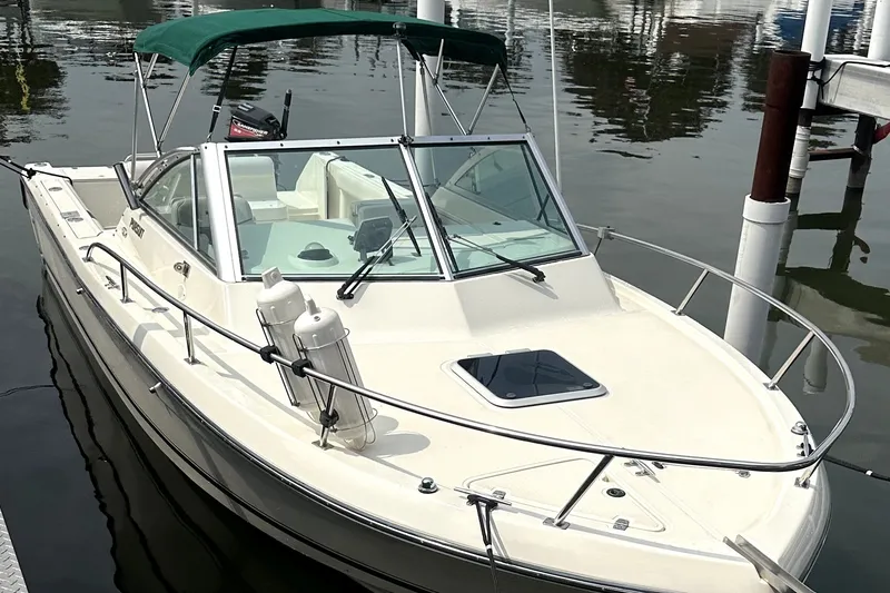 The Image of 1999 Pursuit 2460 Denali boat docked with green canopy and sleek design. - 0