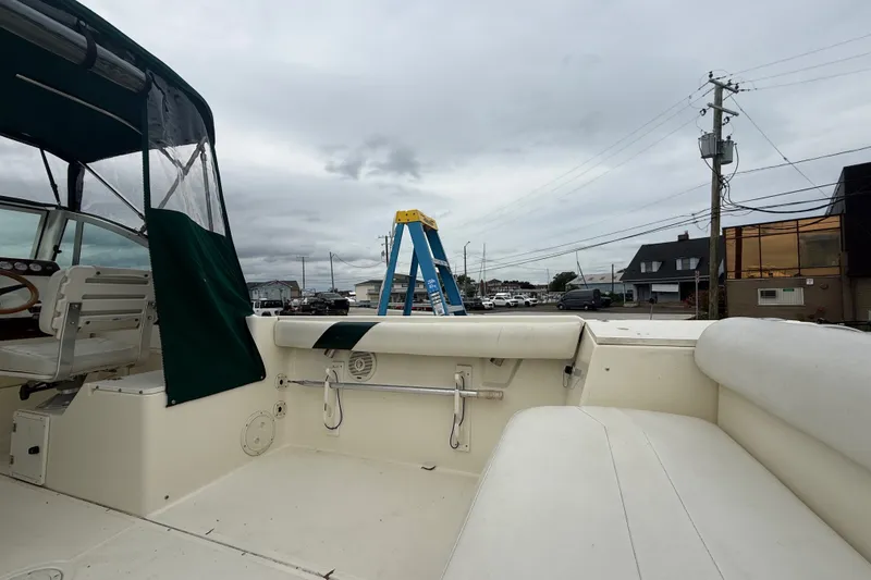 Slide: The Image of 1999 Pursuit 2460 Denali boat interior with seating, ladder, and overcast sky. - 17