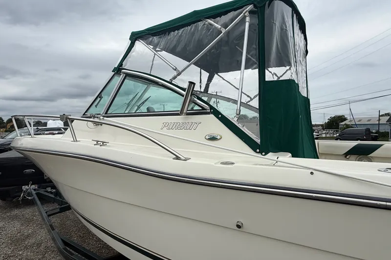 Slide: The Image of 1999 Pursuit 2460 Denali boat with green canopy, parked on a trailer. - 6
