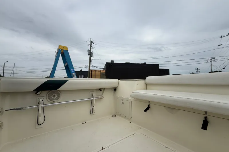 Slide: The Image of 1999 Pursuit 2460 Denali boat interior with seating and storage, under cloudy sky. - 20