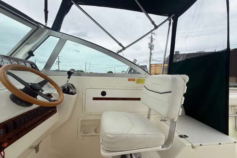 Slide: The Image of 1999 Pursuit 2460 Denali boat cockpit with steering wheel and white captain's chair. - 15