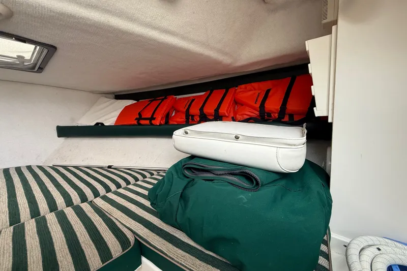 Slide: The Image of Interior cabin of 1999 Pursuit 2460 Denali with striped cushions and life jackets. - 25