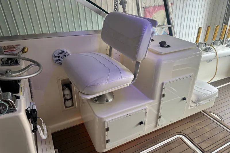 Slide: The Image of Captain's chair and helm on a 2000 Pursuit 3000 Express boat, featuring white upholstery. - 10