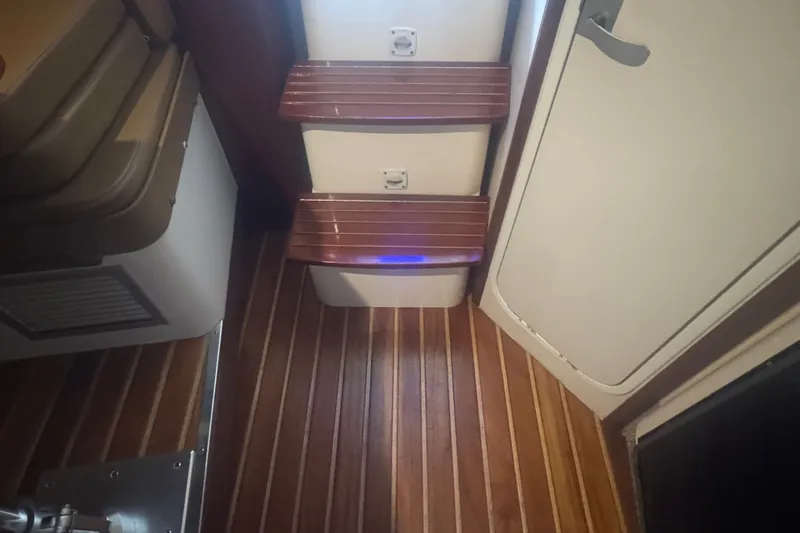 Slide: The Image of Interior of a 2000 Pursuit 3000 Express boat with wooden flooring and steps. - 18