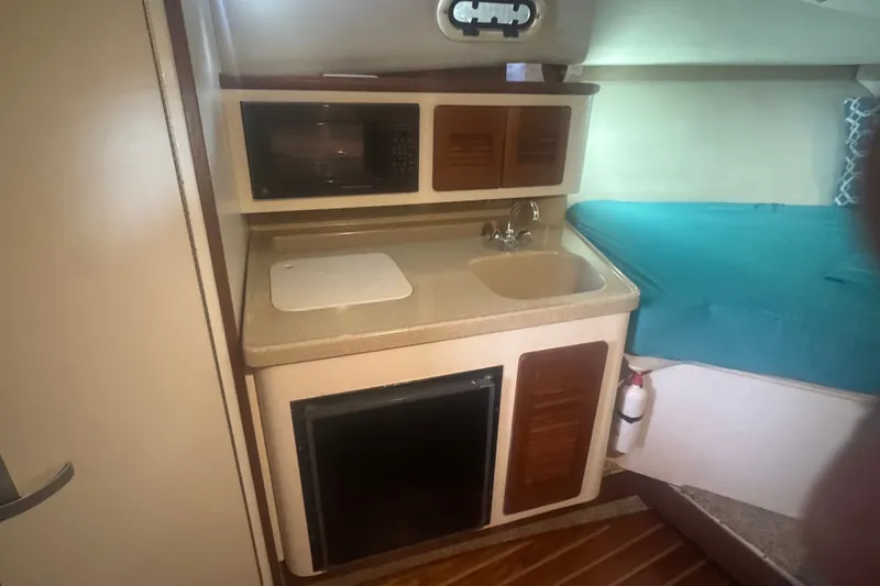 Slide: The Image of Compact kitchen area in a 2000 Pursuit 3000 Express boat with sink and microwave. - 19