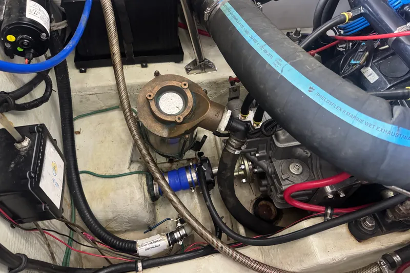Slide: The Image of Engine compartment of a 2000 Pursuit 3000 Express boat, showcasing hoses and mechanical components. - 30