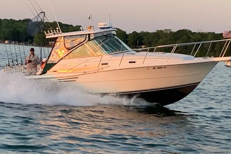 Slide: The Image of 2000 Pursuit 3000 Express boat cruising on a lake at sunset. - 0