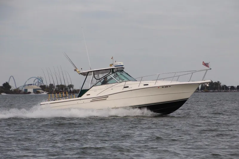 The Image of 2000 Pursuit 3000 Express boat cruising on open water with fishing rods. - 1