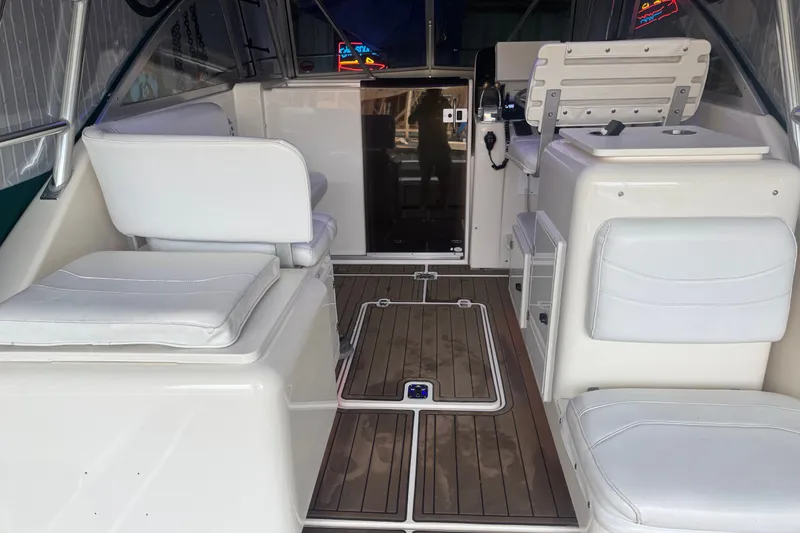 Slide: The Image of Interior of a 2000 Pursuit 3000 Express boat with white seating and wood flooring. - 13
