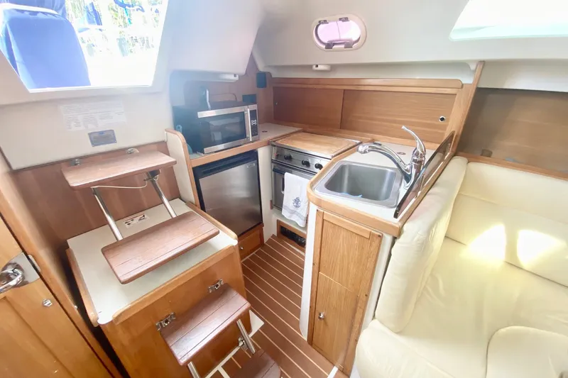 Slide: The Image of Compact kitchen area in a 2007 Catalina 309 sailboat, featuring wood cabinetry and modern appliances. - 28