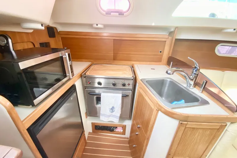 Slide: The Image of Compact kitchen in a 2007 Catalina 309 sailboat with stove, sink, and microwave. - 30