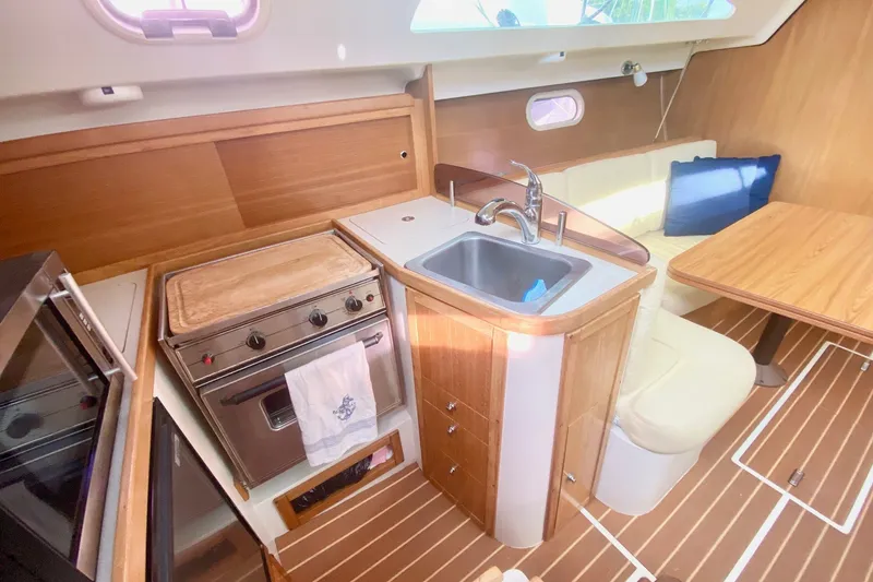 Slide: The Image of Cozy 2007 Catalina 309 yacht interior with kitchen, sink, and dining area. - 29