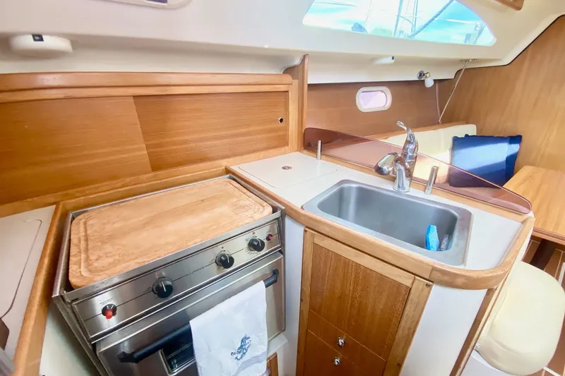 Slide: The Image of 2007 Catalina 309 yacht interior kitchen with stove, sink, and wooden cabinetry. - 31