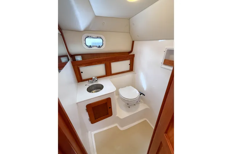 Slide: The Image of 2004 Hunt Yachts Surfhunter 29 interior bathroom with sink, toilet, and wooden cabinetry. - 24