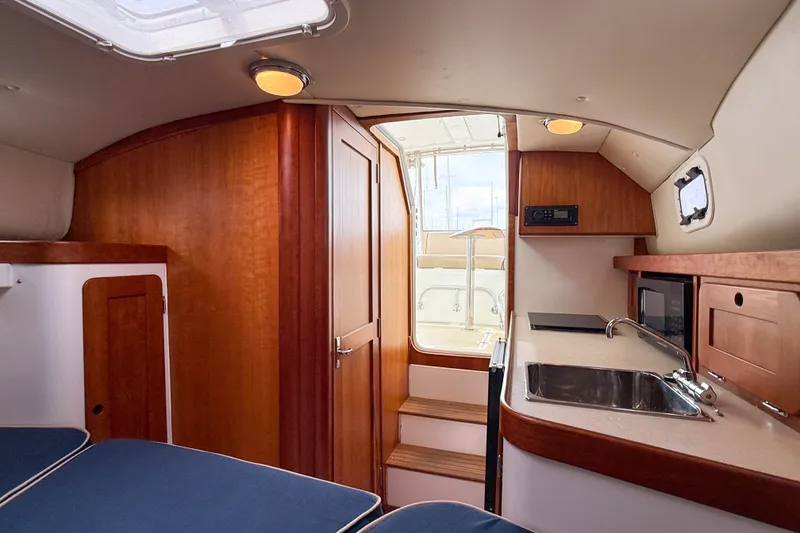 Slide: The Image of Interior of 2004 Hunt Yachts Surfhunter 29, featuring wood cabinetry and compact kitchenette. - 23