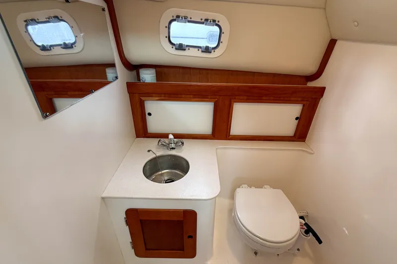 Slide: The Image of 2004 Hunt Yachts Surfhunter 29 bathroom with sink, toilet, and wooden cabinetry. - 25