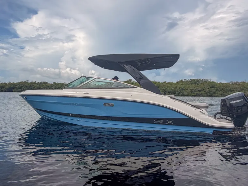 Slide: The Image of The 2027 Sea Ray SLX 260 Outboard is a sleek blue boat with a black canopy. - 25