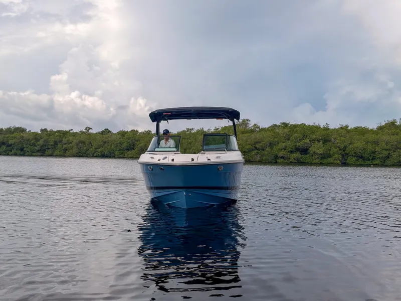 Slide: The Image of A 2027 Sea Ray SLX 260 Outboard on calm water with a green shoreline in the background. - 23