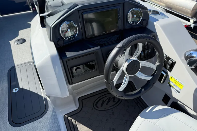 Slide: The Image of 2027 Manitou Encore 25 RF Dual boat dashboard with steering wheel and controls. - 24
