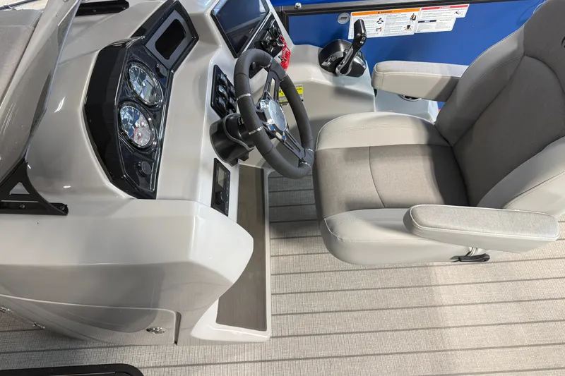 Slide: The Image of 2027 Manitou Encore SL 25 boat cockpit with steering wheel and captain's chair. - 15