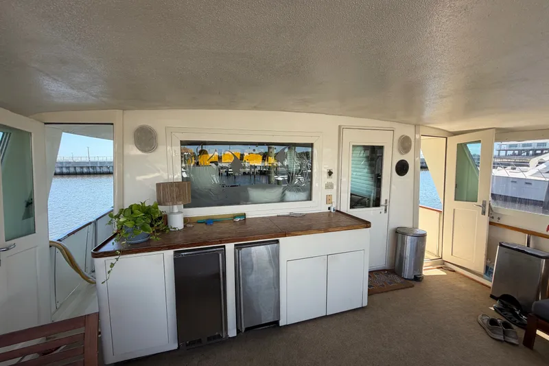 Slide: The Image of 1986 Hatteras 58 Motor Yacht interior with kitchenette, plants, and waterfront view. - 14