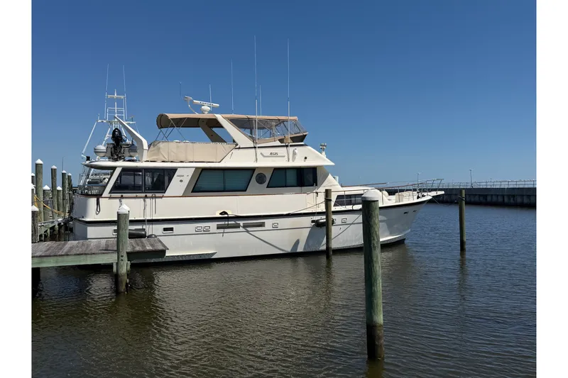 The Image of 1986 Hatteras 58 Motor Yacht docked in a marina under clear blue skies. - 0