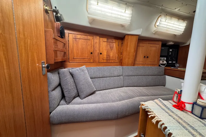 Slide: The Image of Cozy interior of 1991 CS 34 sailboat with wooden cabinets and gray cushioned seating. - 23