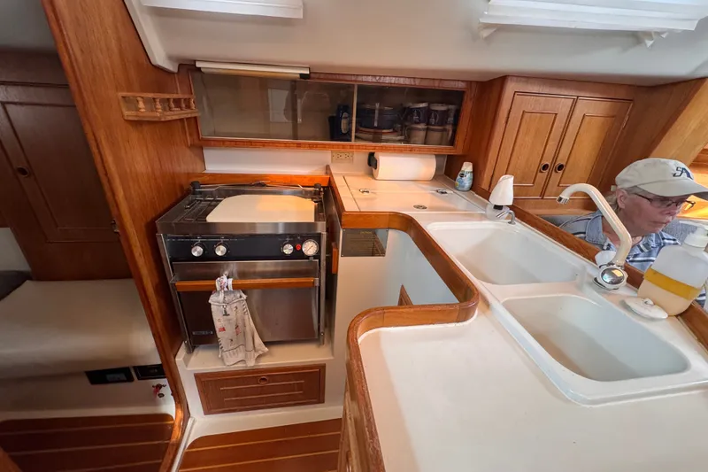 Slide: The Image of Interior of a 1991 CS 34 sailboat galley with stove, sink, and wooden cabinetry. - 25