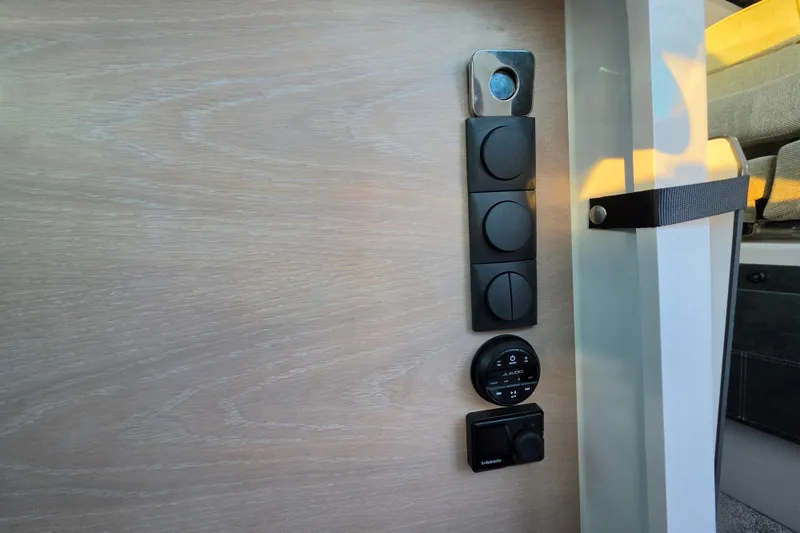 Slide: The Image of Control panel inside 2024 Axopar 45 XC Cross Cabin, featuring sleek black dials and switches. - 18