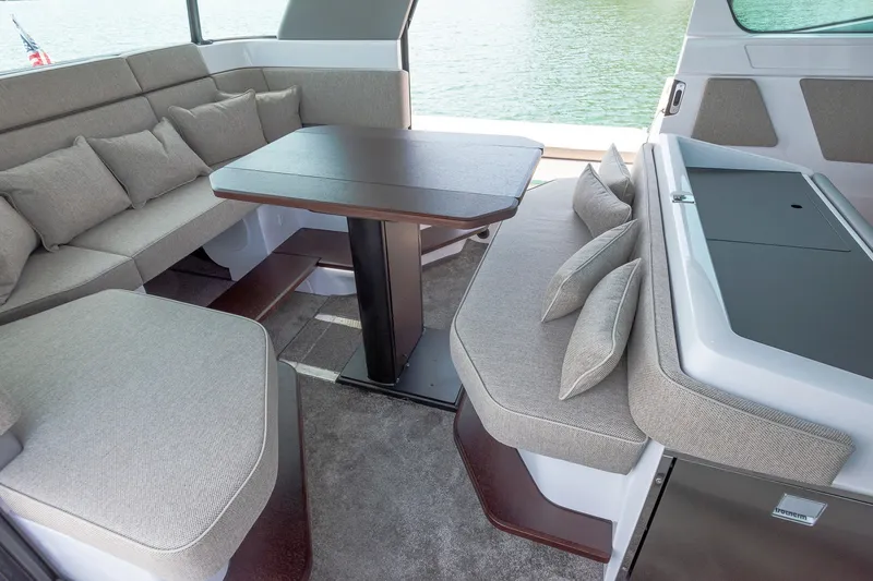 Slide: The Image of 2024 Axopar 45 XC Cross Cabin interior with plush seating and table, overlooking water. - 14