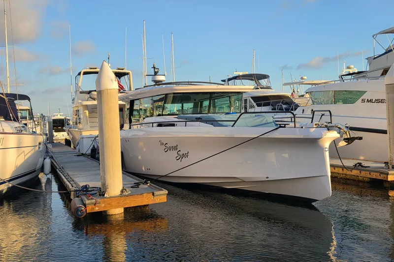 Slide: The Image of 2024 Axopar 45 XC Cross Cabin docked at marina, reflecting in calm water. - 28