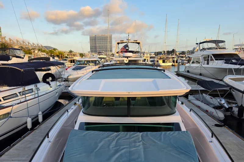 Slide: The Image of 2024 Axopar 45 XC Cross Cabin yacht docked in a marina, surrounded by other boats. - 22