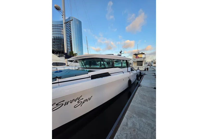 Slide: The Image of 2024 Axopar 45 XC Cross Cabin docked with modern building backdrop. - 24