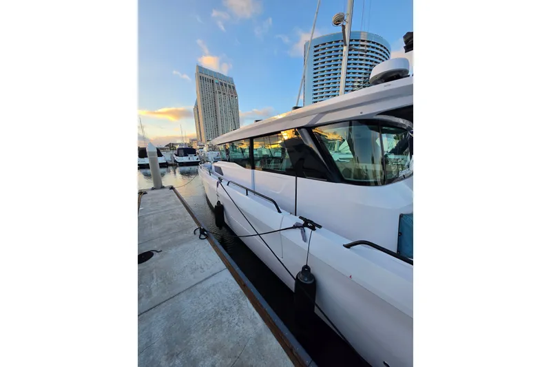 Slide: The Image of 2024 Axopar 45 XC Cross Cabin yacht docked at marina, city skyline in background. - 20