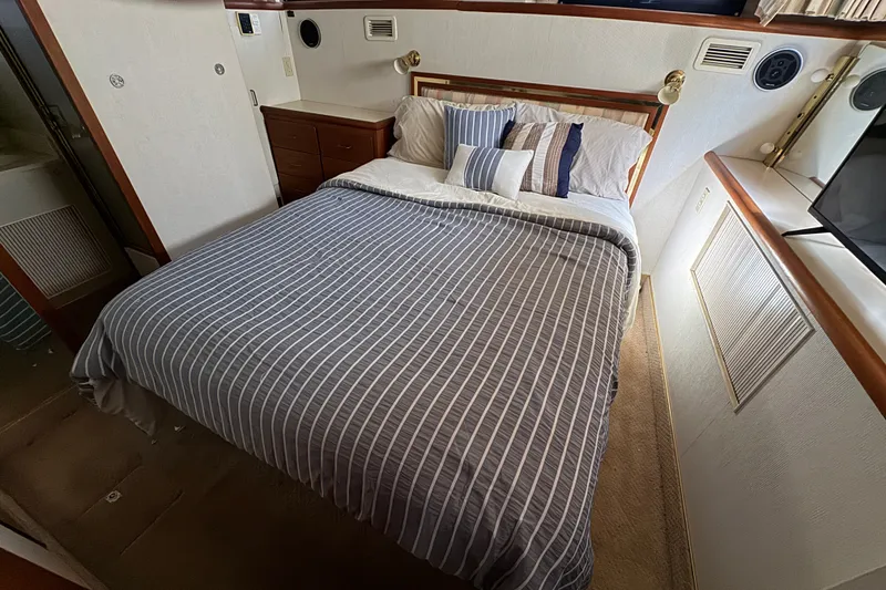 Slide: The Image of Cozy bedroom in 1987 Tollycraft 44 Cockpit Motor Yacht with striped bedding and wood accents. - 15