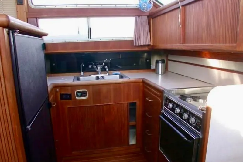 Slide: The Image of 1987 Tollycraft 44 Cockpit Motor Yacht kitchen with wood cabinetry, stove, and sink. - 10