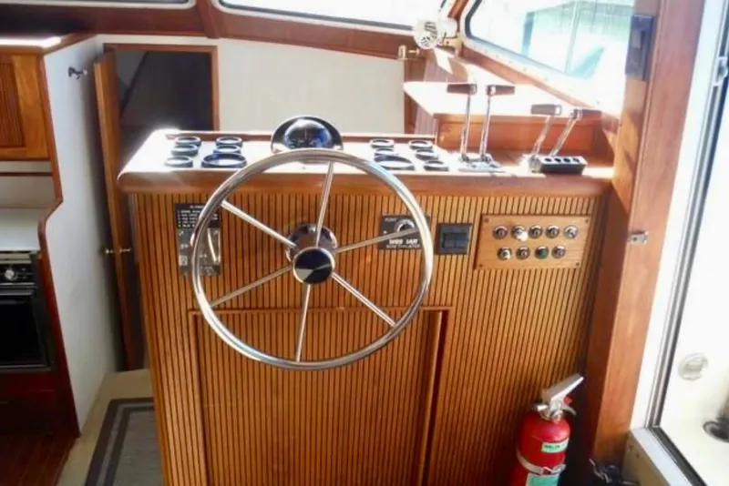 Slide: The Image of 1987 Tollycraft 44 Cockpit Motor Yacht helm with wooden paneling and steering wheel. - 4