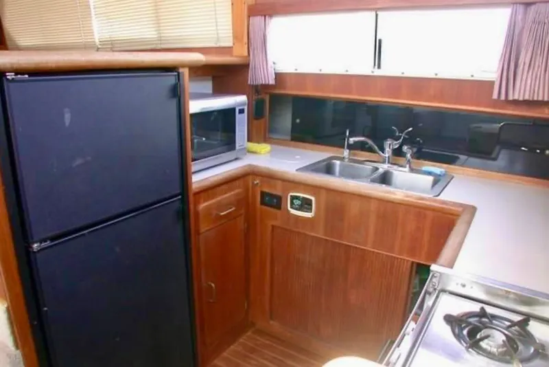 Slide: The Image of 1987 Tollycraft 44 Cockpit Motor Yacht kitchen with sink, stove, and microwave. - 8