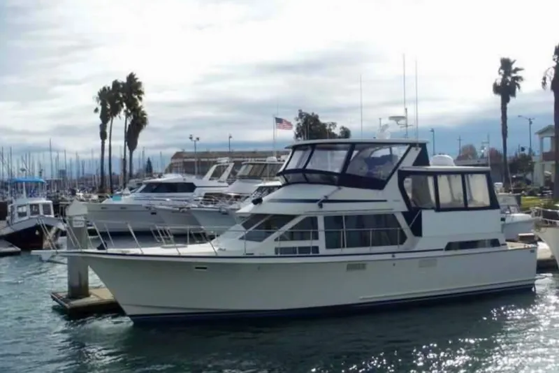 Slide: The Image of 1987 Tollycraft 44 Cockpit Motor Yacht docked at a marina with palm trees. - 3
