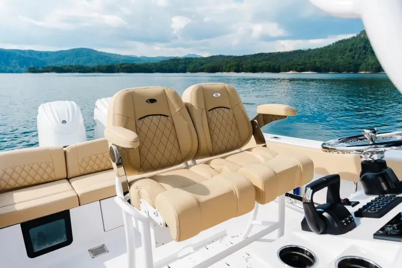 Slide: The Image of 2027 Sportsman Heritage 251 Center Console boat interior with tan seating and scenic lake view. - 10
