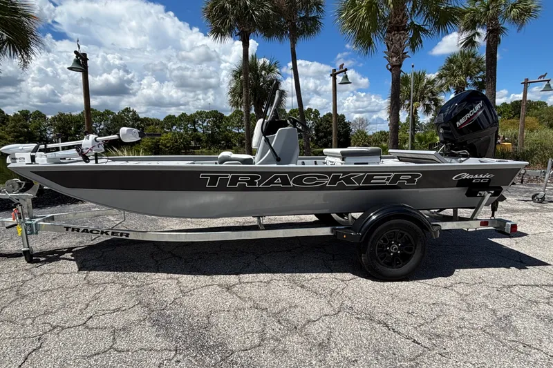 The Image of 2027 Tracker Bass Tracker Classic CC boat on trailer, parked outdoors under palm trees. - 0