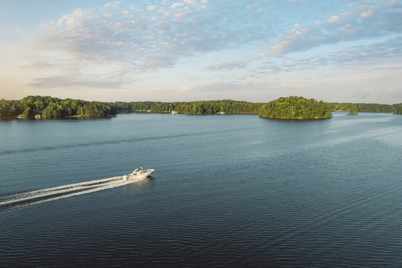 Slide: The Image of A 2027 Sea Ray SDX 270 Outboard cruising on a calm lake with wooded islands. - 7