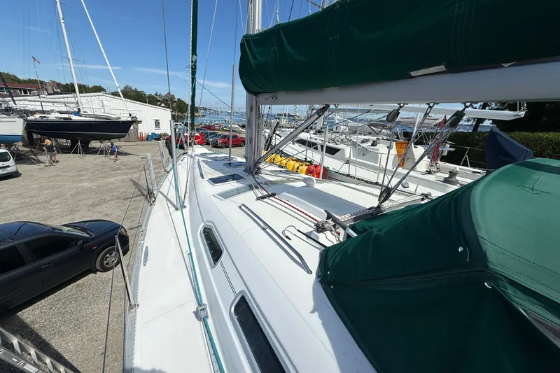 Slide: The Image of 2003 Beneteau Oceanis Clipper 393 sailboat docked at a marina with green covers. - 2