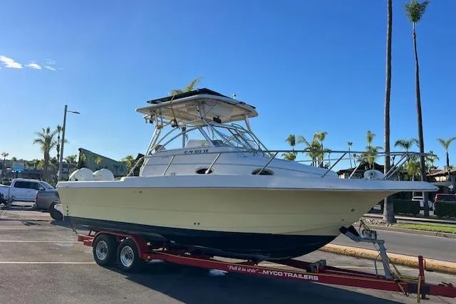 Slide: The Image of 1998 Pro-Line 2610 Walkaround boat on trailer, parked outdoors under clear blue sky. - 35