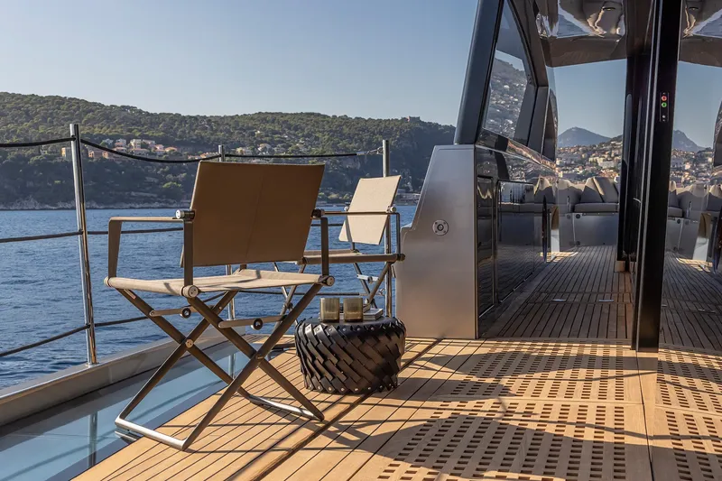 Slide: The Image of Luxurious 2026 Pershing GTX116 yacht deck with chairs, overlooking scenic coastal view. - 13