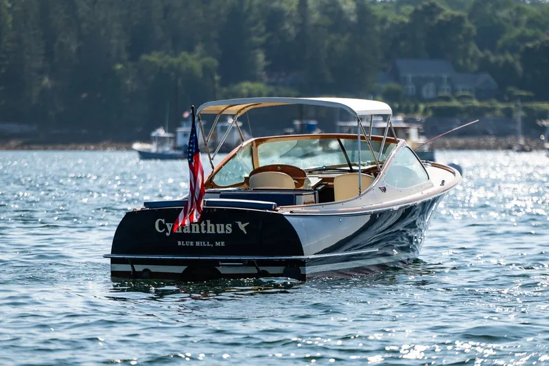 Slide: The Image of 2008 Hinckley Talaria 29R boat on water, displaying American flag, scenic background. - 35