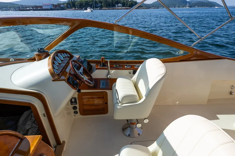 Slide: The Image of 2008 Hinckley Talaria 29R cockpit with elegant white seating and wooden dashboard, overlooking serene waters. - 19