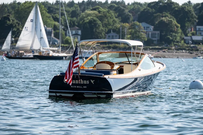 Slide: The Image of 2008 Hinckley Talaria 29R boat on water, displaying American flag, with sailboats in background. - 32